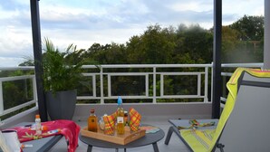 A balcony with two lounge chairs, a table with beverages and snacks, and a potted plant. - Logement "paprika" 2 À 6 Pers (Le Gosier)
