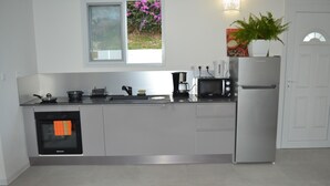 A modern kitchen with a built-in oven, a coffee maker, and a refrigerator. - Logement "paprika" 2 À 6 Pers (Le Gosier)