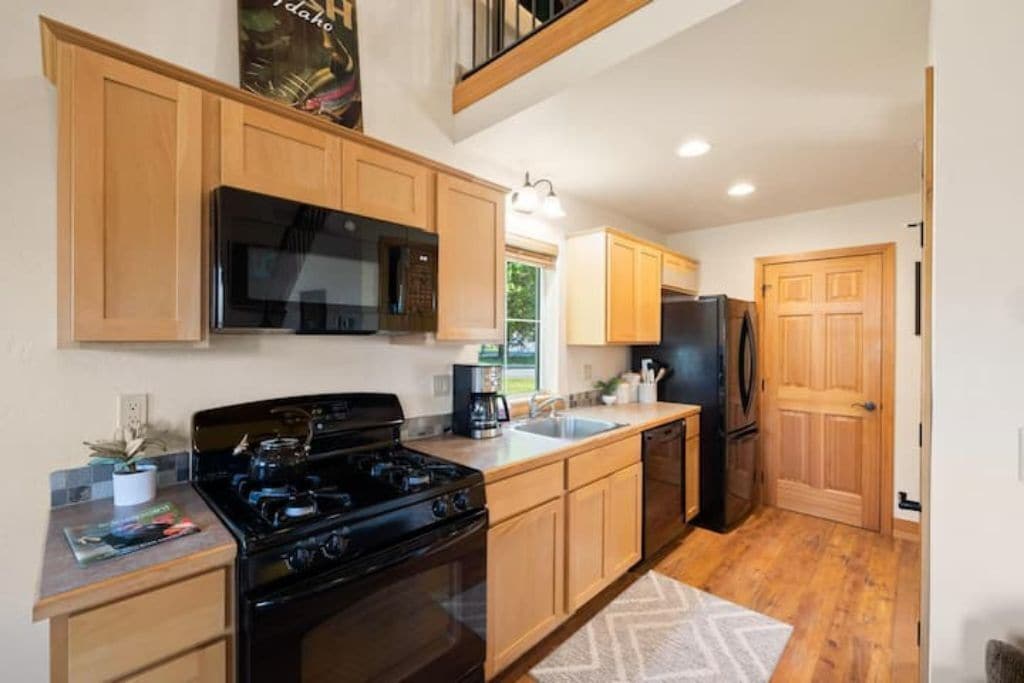 A modern kitchen with wooden cabinets, a black stove, a microwave, and a refrigerator.