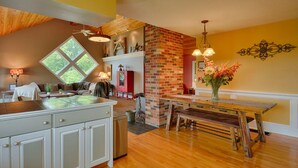 Una cucina con isola in legno, parete decorata con mattoni e zona pranzo con panche.