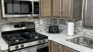 Uma cozinha moderna com eletrodomésticos de aço inoxidável, armários de madeira, painel de azulejos e forno embutido.