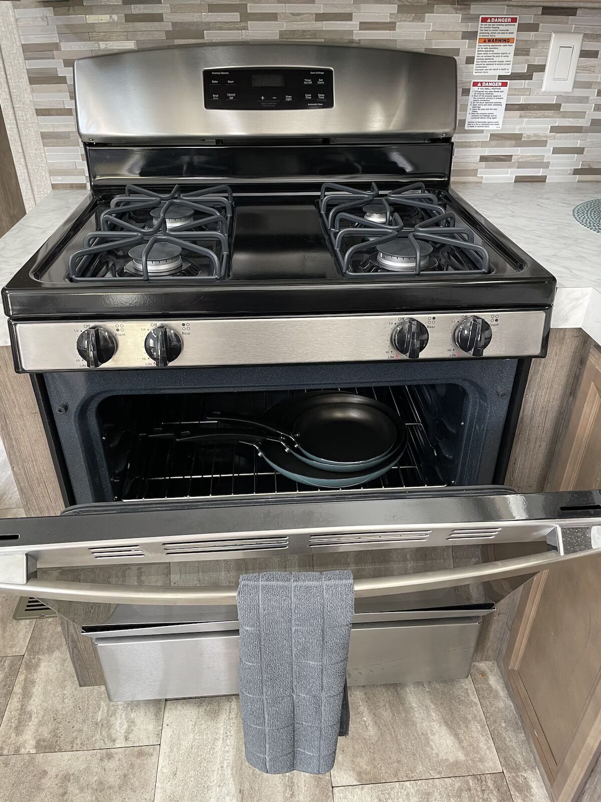 Une cuisinière en acier inoxydable dotée de quatre brûleurs, d’un four intégré et d’un panneau frontal en acier inoxydable.