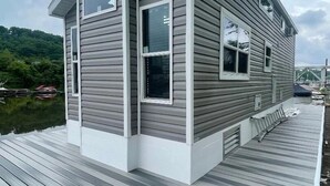 Uma casa de dois andares com revestimento cinza e um deck de madeira.