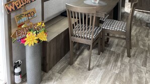 Uma sala de jantar com mesa de madeira, duas cadeiras, um lustre e uma placa com a inscrição 'Welcome to Paradise'.