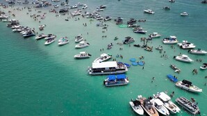 Un puerto deportivo con numerosas embarcaciones amarradas y gente caminando.