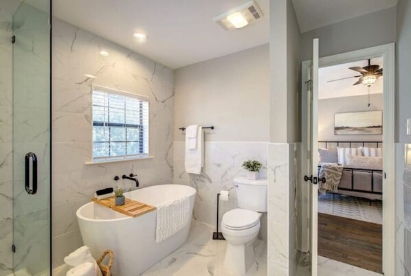 Un baño moderno con una bañera independiente, inodoro y zona de ducha.