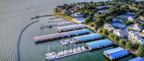 An aerial view of a marina with docked boats, a swimming pool, and residential buildings.