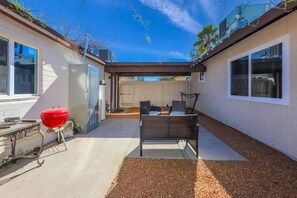 A covered patio area with a grill, outdoor furniture, and a view of the backyard. - Arizona Mesquite Home (Tucson)