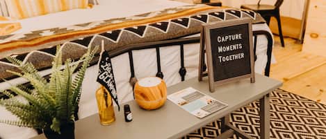 Un dormitorio ordenado con una cama, una mesita de noche con un cartel, una planta en maceta y un cuenco decorativo.