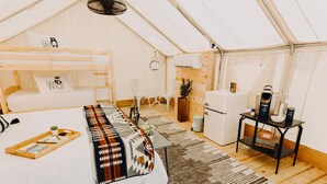 Alojamiento con carpa que incluye una litera, una pequeña kitchenette, una mesa con una planta y un calentador.