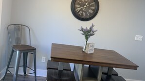 Un comedor con mesa de madera, sillas de metal, un reloj de pared y una araña.