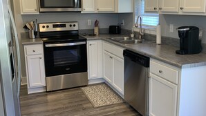 Una cocina moderna con armarios blancos, electrodomésticos de acero inoxidable y piso gris.