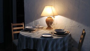 Un tavolo da pranzo con una tovaglia a righe, una lampada da tavolo in vimini e alcuni bicchieri e piatti da vino.