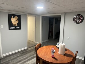 Relax in this cozy space with a dining table and chairs, a dartboard, and a unique poster on the wall.