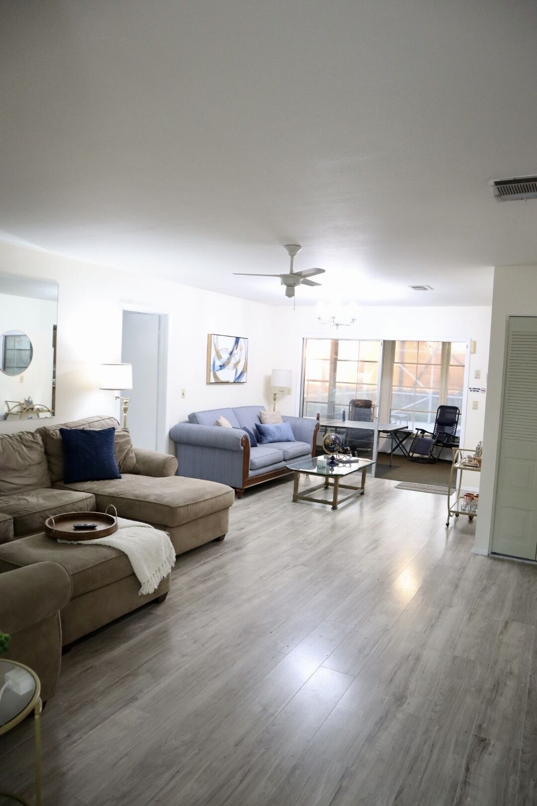 A spacious living room with a large sofa, a coffee table, and a ceiling fan.