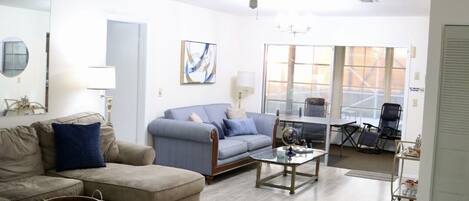 A spacious living room with a large sofa, a coffee table, and a ceiling fan.