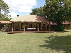 Ein zweigeschossiges Haus mit Ziegeldach, einer Laube und einem Rasen.