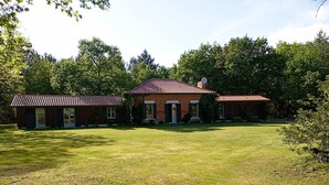 A two-story brick house with a red-tiled roof, a front porch, and a well-maintained lawn. - Maison Landaise Rénovée au Milieu de 2 Hectares (Sanguinet)