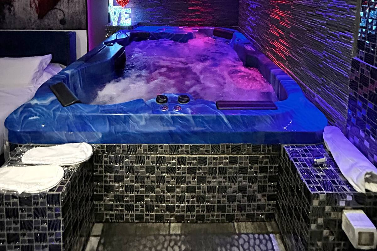 A modern spa room with a hot tub, tiled walls, and ambient lighting.