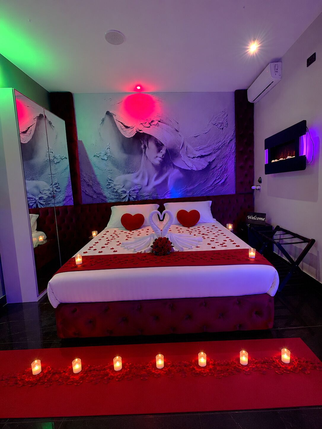 A bed with a red and white bedspread, heart-shaped pillows, and a bouquet of flowers.