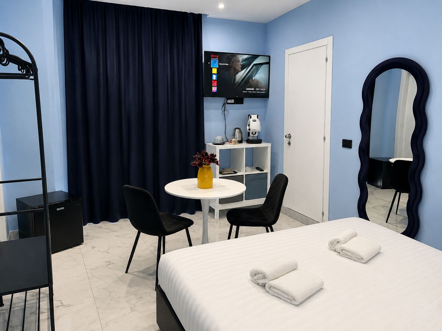 A hotel room with a bed, a desk, a chair, a TV, and a mirror.