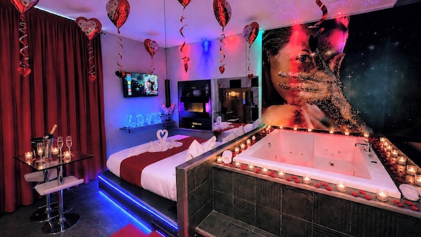 Um quarto luxuoso com uma cama grande, uma banheira e uma televisão.