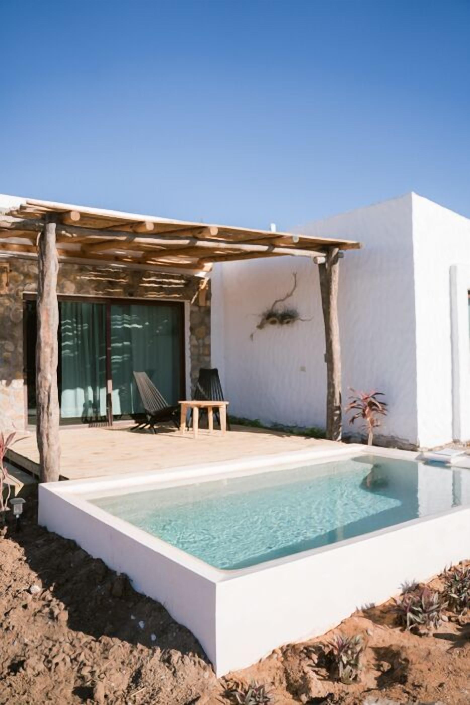 Et moderne poolområde med pergola, liggestole og et klart pool.