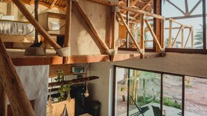 A rustic wooden interior with a high ceiling, a wooden table, and a view of the outdoors through large windows. - Toninas México (Elota)