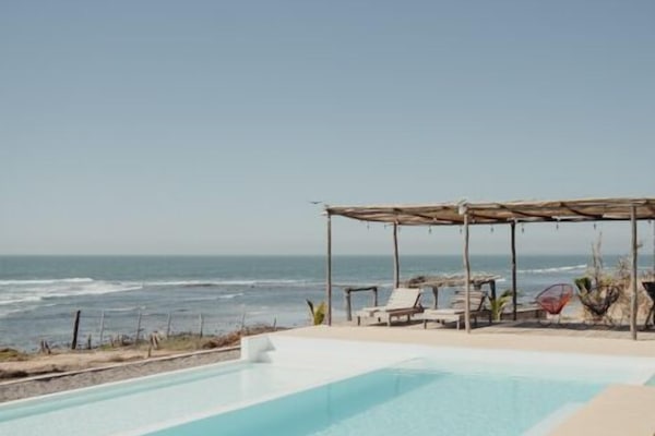 Una piscina al aire libre, sombrillas, sillones reclinables de piscina