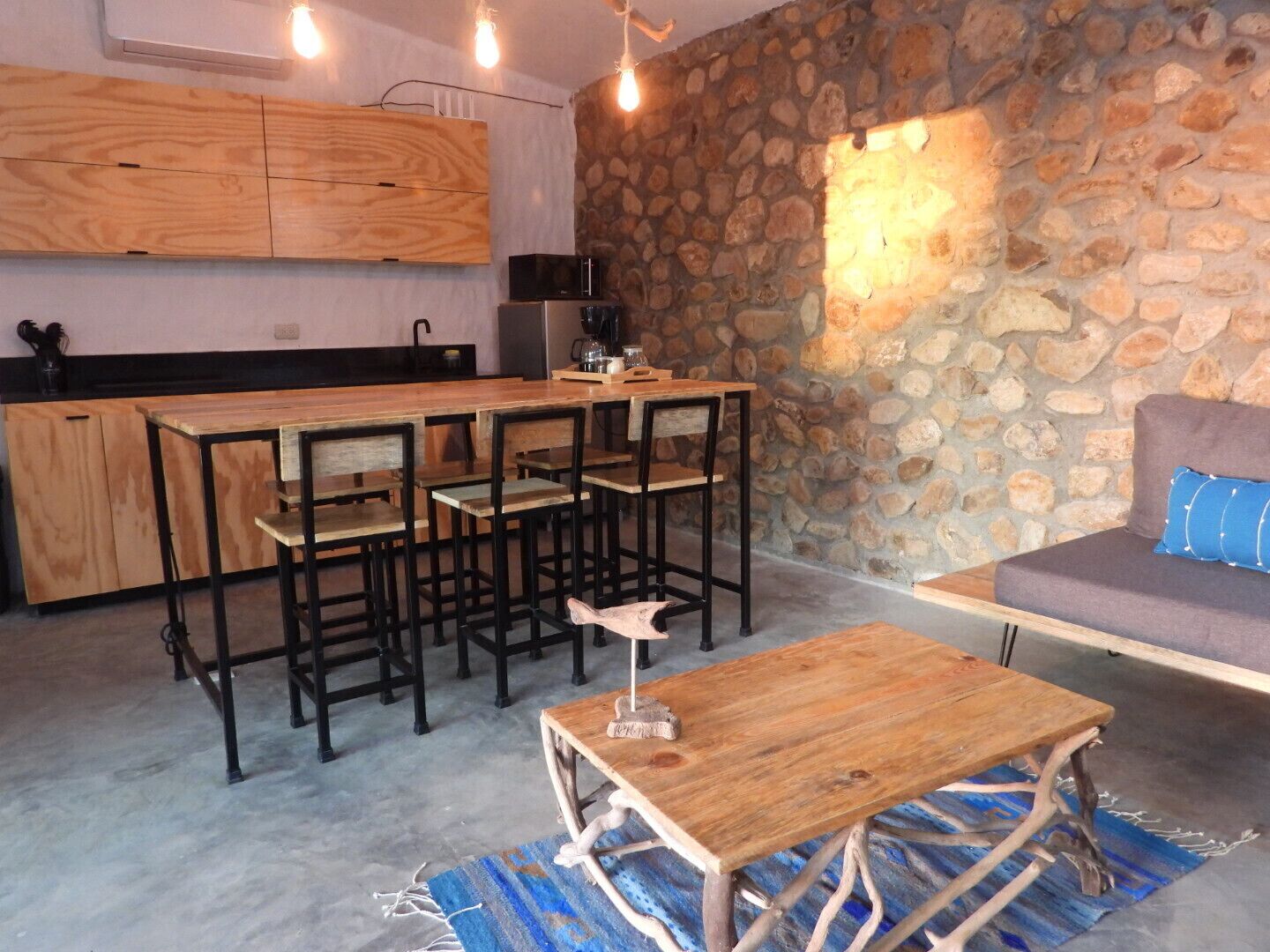 Une cuisine moderne avec un mur en pierre, des armoires en bois et un coin bar avec des tabourets.
