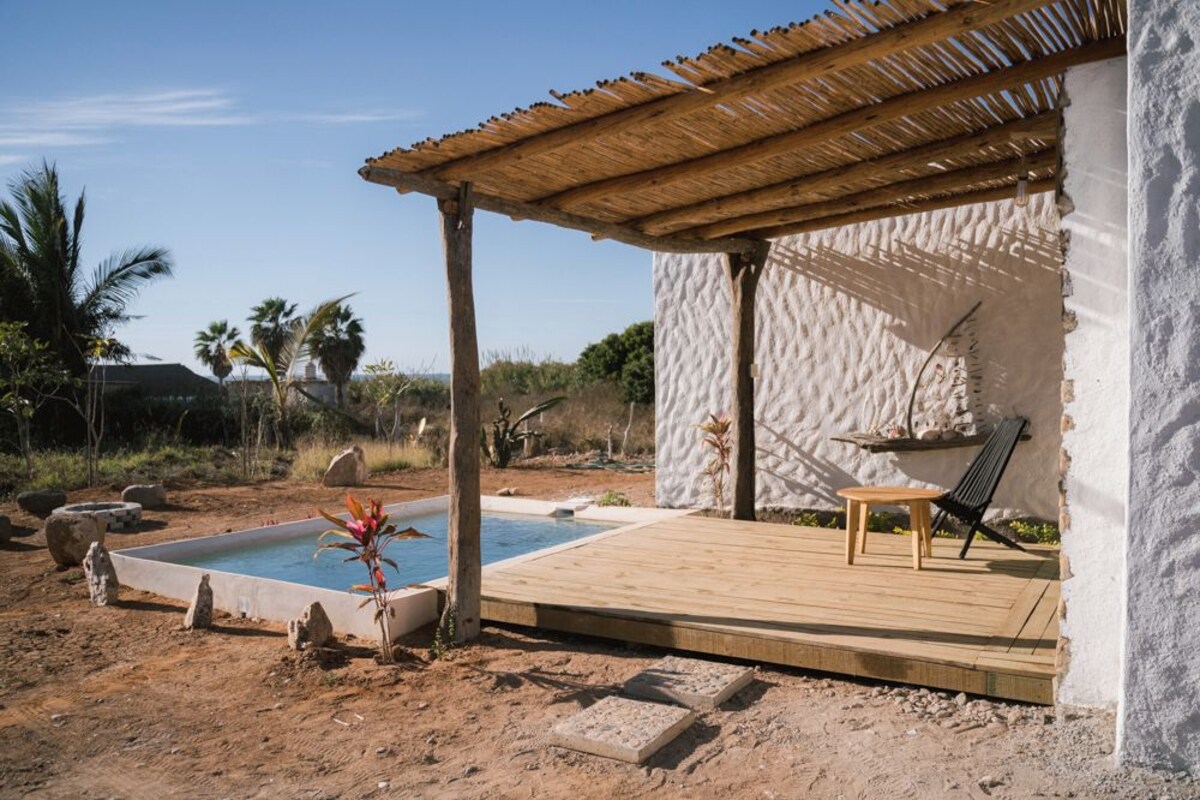 A pool area with a wooden deck, a hanging chair, and a small table.