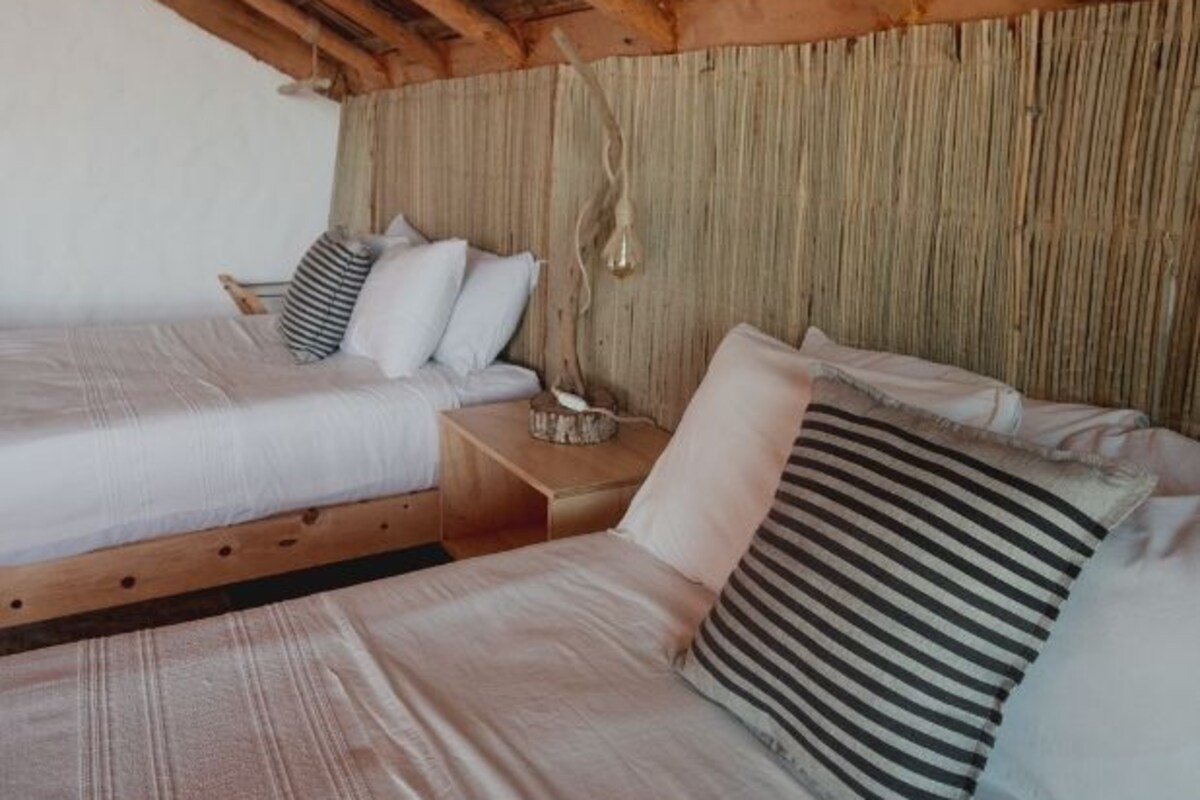 A cozy room with two beds, wooden beams on the ceiling, and a simple, rustic design.