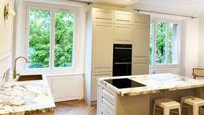 Une cuisine moderne avec des meubles blancs, un plan de travail en marbre et un four encastré.