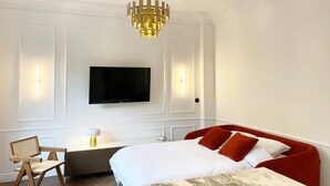 Une chambre d’hôtel avec un grand lit, un téléviseur fixé au mur et un bureau avec une chaise.