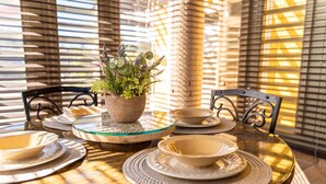 A dining table with plates, bowls, and a woven basket with greenery, set against a window with blinds. - CASA CANAVERAL-TropicalPrivatePool-14Family-sized! Near Rafael Hernandez Airport (Isabela)