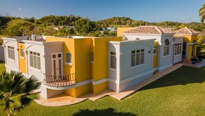 A modern building with a yellow facade, large windows, and a balcony. - CASA CANAVERAL-TropicalPrivatePool-14Family-sized! Near Rafael Hernandez Airport (Isabela)