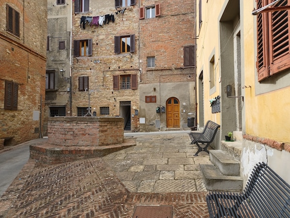 A narrow cobblestone street with a bench and a wooden door.