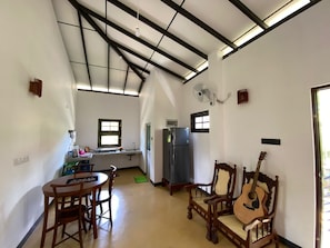 Cozy living space with a high ceiling and exposed beams, featuring a dining area and basic amenities.