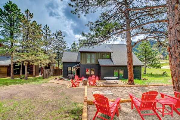 Une cabane dotée d’une terrasse avec des fauteuils Adirondack rouges et un foyer.