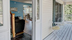 Un porche abrité avec un paillasson, un coin repas avec une table et des chaises, et une vue sur l’intérieur de la maison.