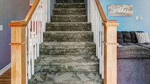 Un escalier avec des rampes en bois et des marches recouvertes de moquette, menant à un palier.