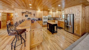 A spacious kitchen with wooden cabinets, a central island, and bar stools.