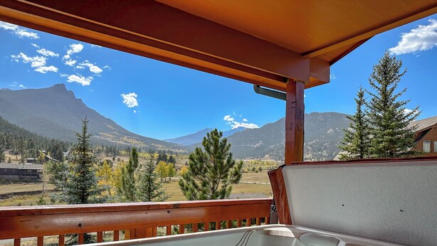 A hot tub on a wooden deck with a mountain view.