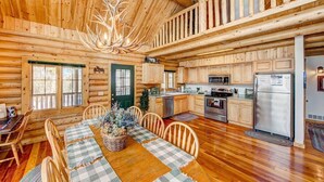 A log cabin interior with a dining area, kitchen, and a balcony. - Moose Mountain Lodge - Secluded Log Home w/Beautiful Mountain Views (Estes Park)