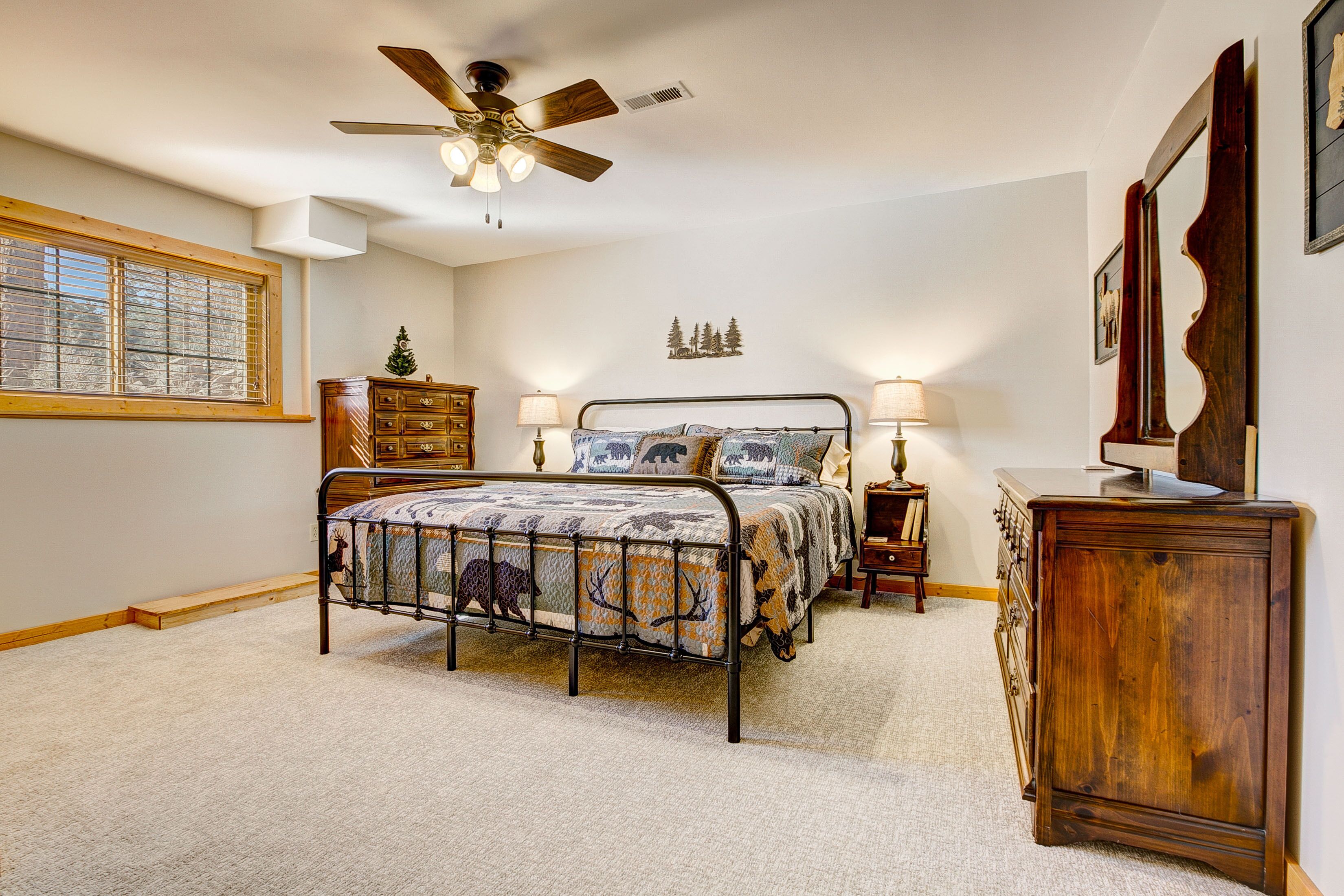 A bedroom with a bed, a dresser, a nightstand, a ceiling fan, and a window.