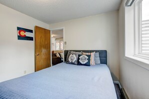 A bedroom with a bed, a door, a window, and a wall-mounted artwork. - Ridge View - Mountain Top Home with 360 Views (Estes Park)