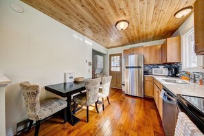 A kitchen with wooden ceiling, a dining table with chairs, a refrigerator, and a microwave. - Ridge View - Mountain Top Home with 360 Views (Estes Park)