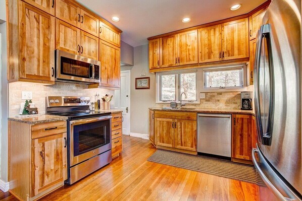 A kitchen with wooden cabinets, stainless steel appliances, and a window providing natural light.