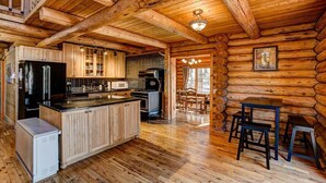 A log cabin interior with a kitchen, dining area, and a large wooden ceiling. - Windham Drive - Beautiful Secluded Mountain Home (Estes Park)