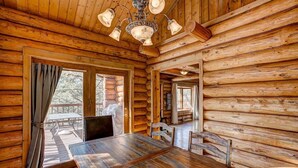 A wooden cabin interior with a dining table, chairs, and a chandelier. - Windham Drive - Beautiful Secluded Mountain Home (Estes Park)